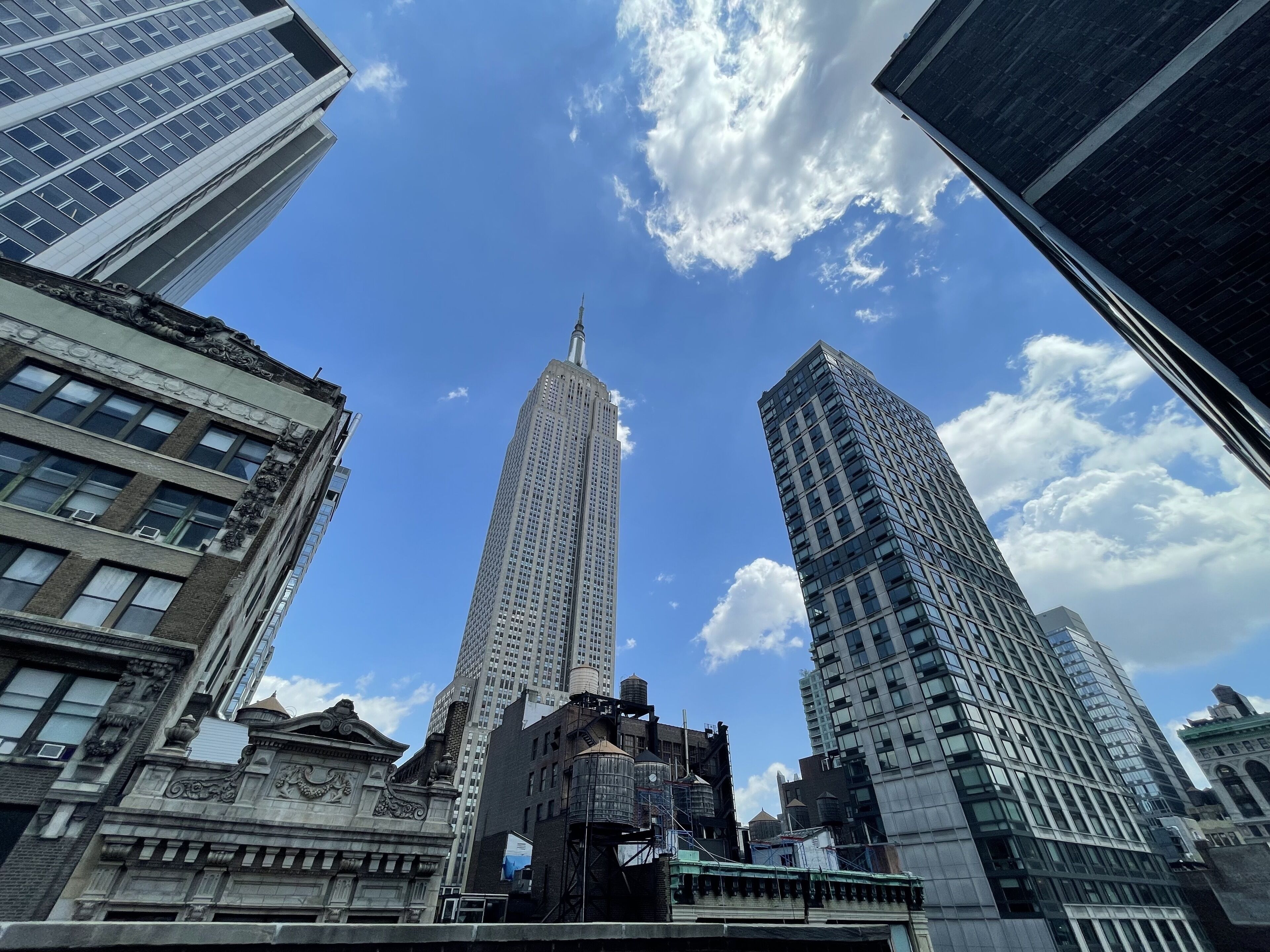 Un paisaje urbano con edificios altos, incluyendo un rascacielos destacado con aguja, rodeado de otras estructuras elevadas.