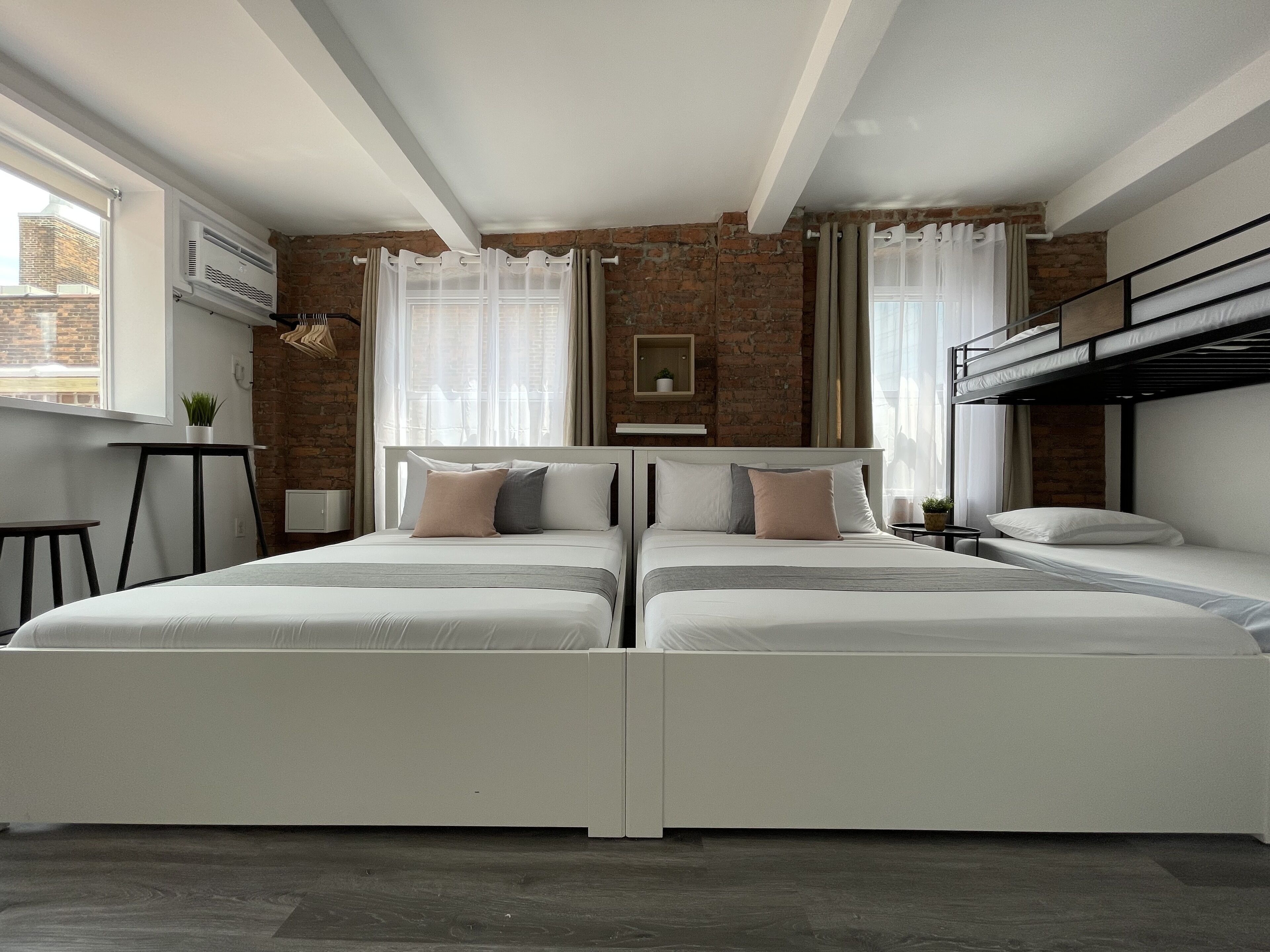 A modern bedroom with two beds, a brick wall, and a loft bed.