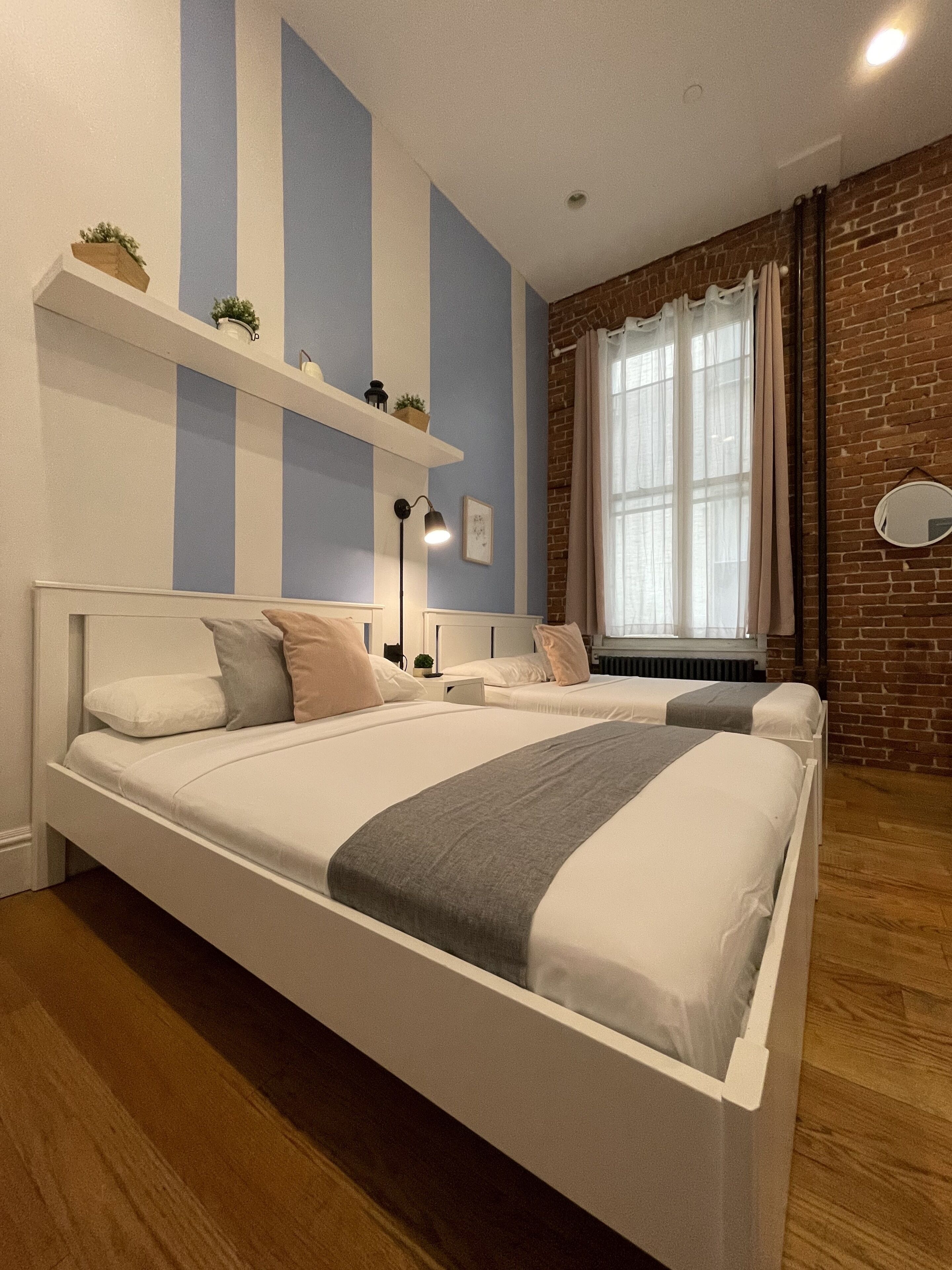 A bedroom with a large bed, a brick wall, and a window with curtains.