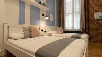 A bedroom with a large bed, a brick wall, and a window with curtains.