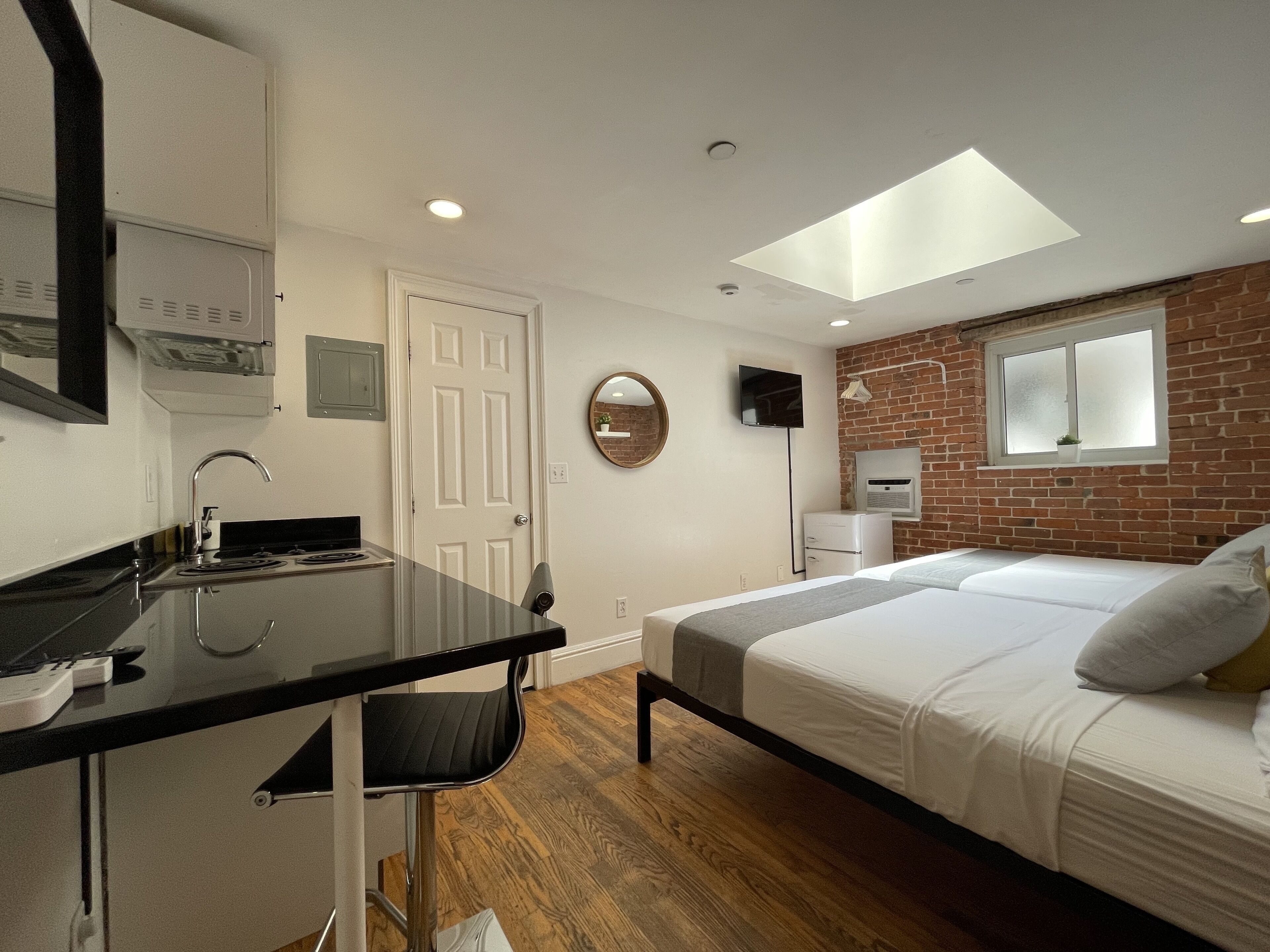 Une chambre d’hôtel moderne équipée d’un lit, d’un bureau, d’un miroir, d’une télévision et d’une fenêtre de toit.