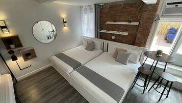 Ein modernes Schlafzimmer mit einem großen Bett, Nachttischen, einem runden Spiegel und einer Ziegelwand.