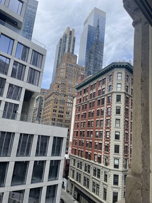 Un paysage urbain comprenant des bâtiments modernes et historiques, notamment un imposant bâtiment en briques rouges agrémenté de détails blancs et un grand gratte-ciel en verre.