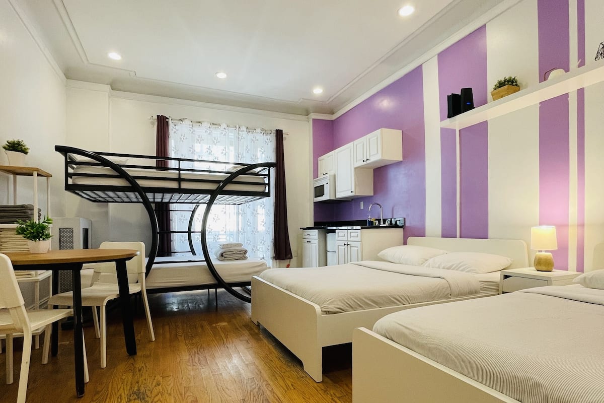 A modern bedroom with a bunk bed, a desk, and a kitchenette.