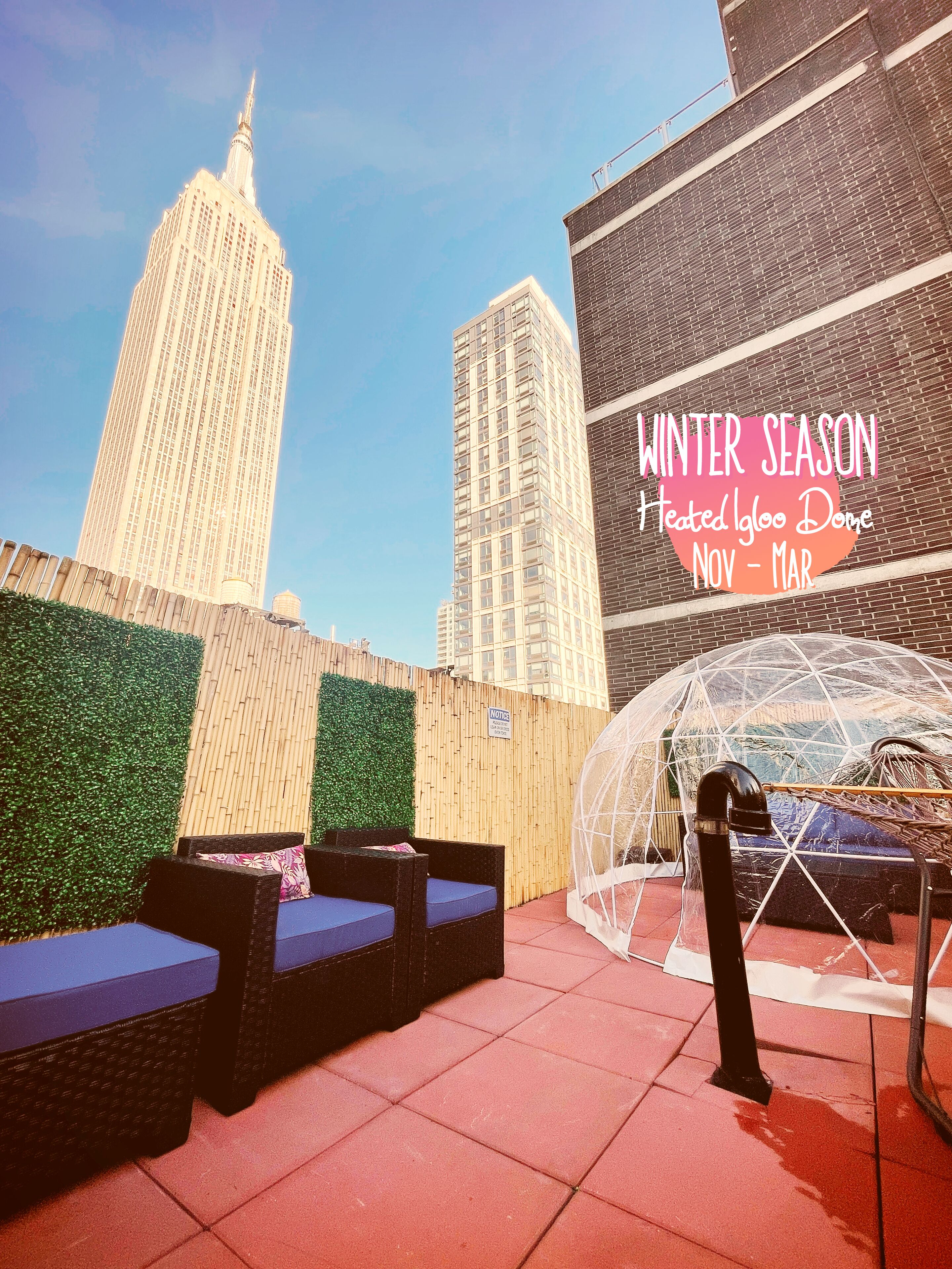 Terraza en la azotea con mobiliario, una estructura con cúpula transparente y vistas a edificios altos.