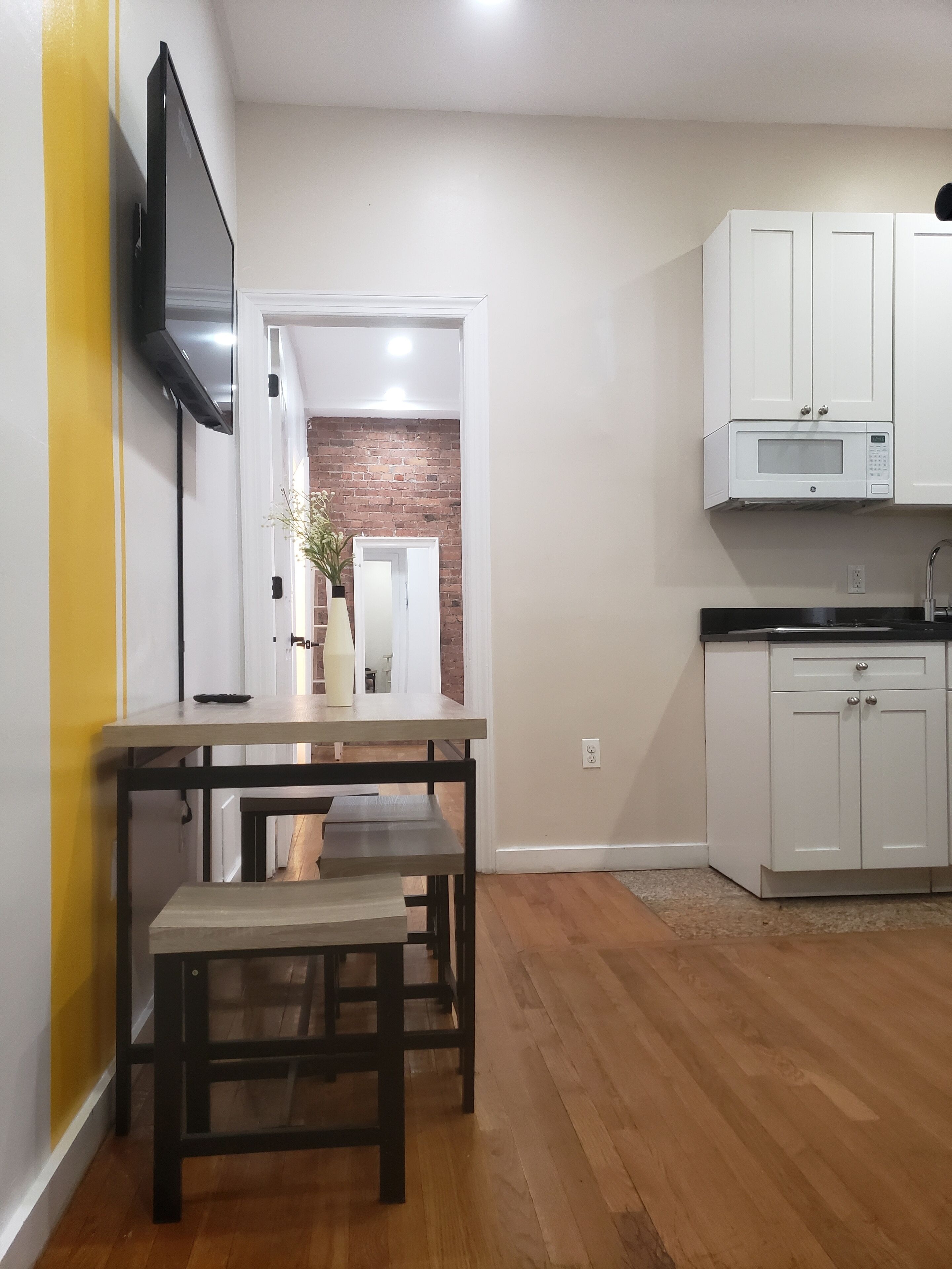 Una cocina moderna con armarios blancos, un microondas integrado y un banco de madera.