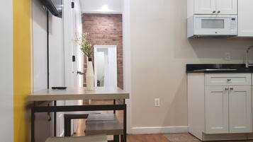 Una cocina moderna con armarios blancos, un microondas integrado y un banco de madera.