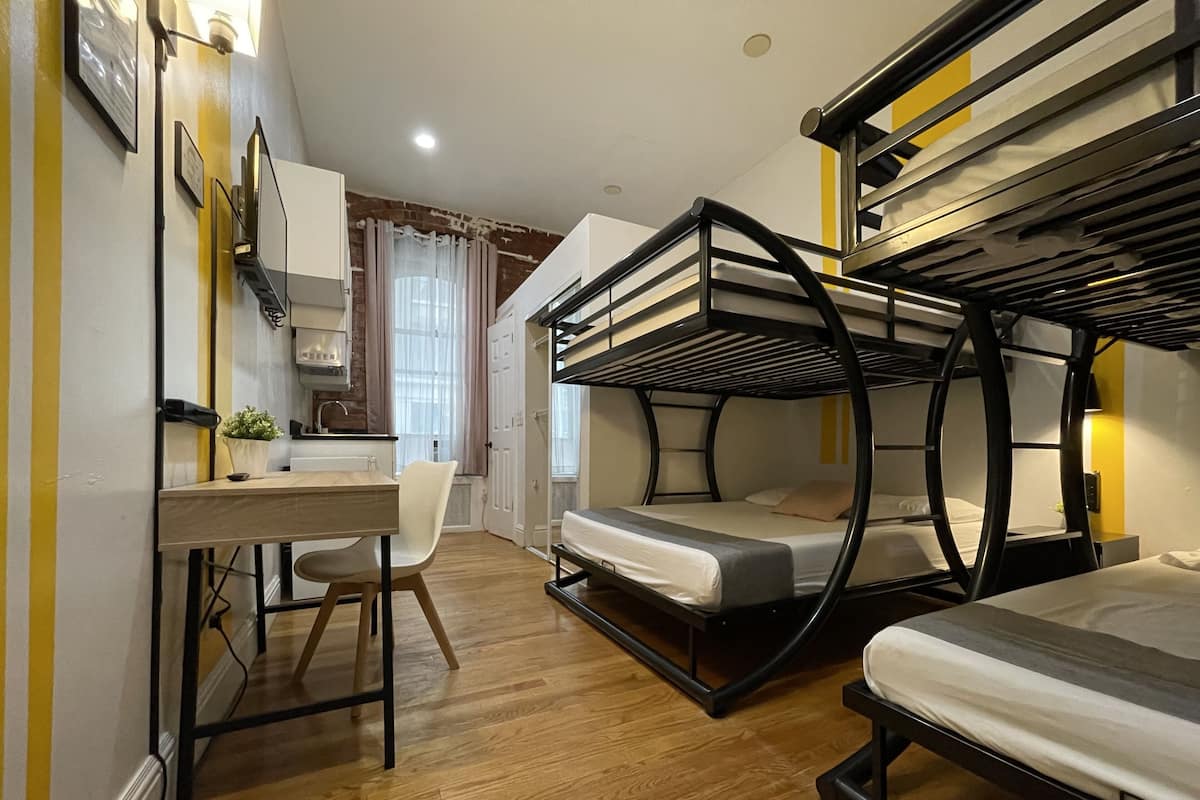 A compact room with bunk beds, a desk, and a chair.
