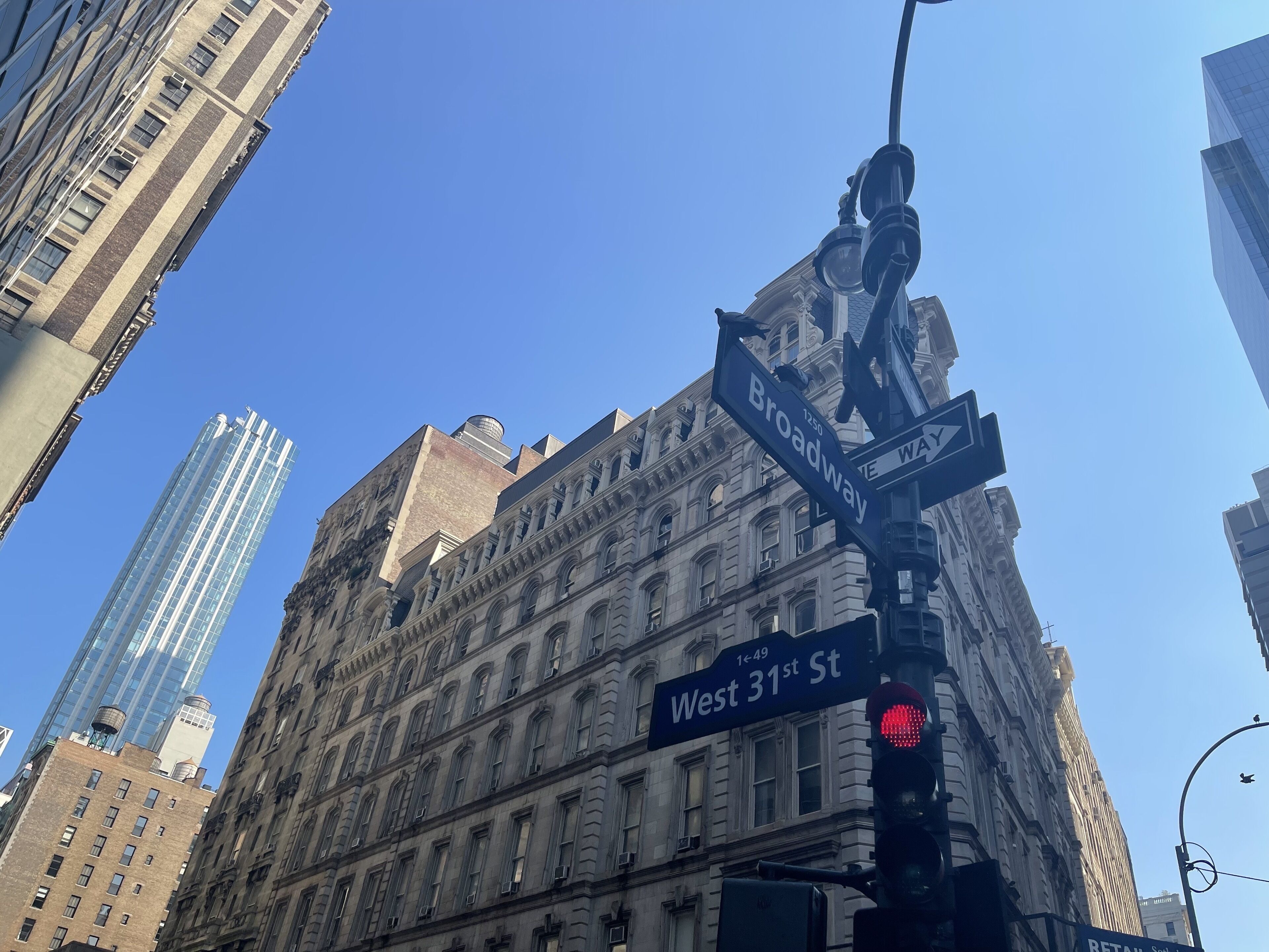 A street intersection with a traffic light and street signs for Broadway and West 31st St.