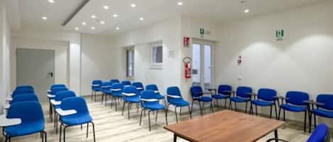 A conference room with blue chairs, a wooden table, and a tiled floor.
