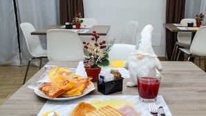 A breakfast setting with a plate of toast, ham, and a drink, a small potted plant, and a white gnome figure on a table.