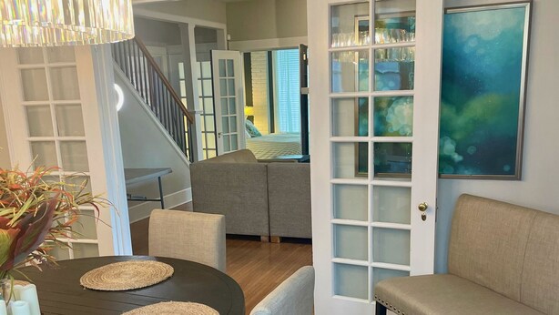 A dining area with a round table, chairs, a chandelier, and a view into a bedroom through an open door. - The Belmont - Lux Abode with Pool on Belmont Blvd (Nashville)