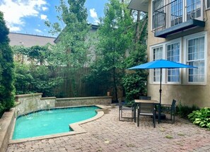 A backyard with a swimming pool, patio furniture, and a blue umbrella.