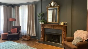 A living room with a fireplace, a large mirror, and a comfortable seating area. - The Belmont - Lux Abode with Pool on Belmont Blvd (Nashville)