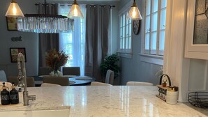 A modern kitchen with a central island, stainless steel appliances, pendant lighting, and a view to the dining area. - The Belmont - Lux Abode with Pool on Belmont Blvd (Nashville)