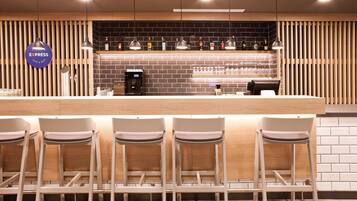 Zona de bar con mostrador, taburetes y una variedad de botellas en estanterías.