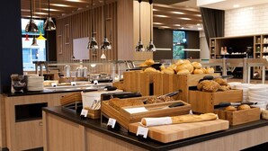Ein Frühstücksbuffet mit verschiedenen Brotsorten, Gebäck und Besteck.
