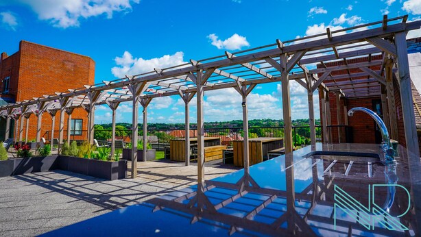 A rooftop patio with a pergola, outdoor seating, and a modern kitchen area. - Luxury Stevenage Town Centre Apartment (Stevenage)
