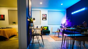 A modern living room with a sofa, a dining table, and a neon sign. - Luxury Stevenage Town Centre Apartment (Stevenage)