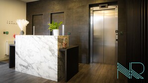 A reception area with a marble counter, a potted plant, and an elevator. - Luxury Stevenage Town Centre Apartment (Stevenage)