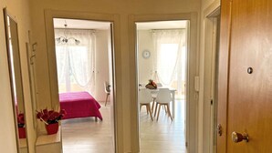 Un pasillo que conduce a un dormitorio con cama y una zona de comedor con sillas y mesa.