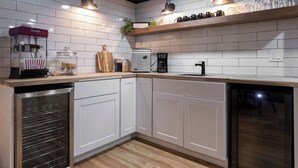 A modern kitchen with white cabinets, a built-in oven, a coffee maker, and a popcorn machine.