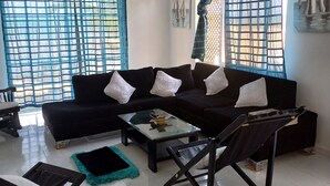 A living room with a black sofa, a glass coffee table, and a black armchair.