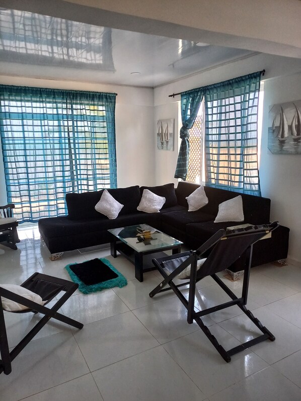 A living room with a black sofa, a glass coffee table, and a black armchair.