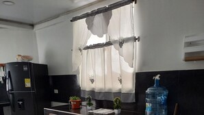 A compact kitchen with a refrigerator, a water dispenser, a sink, and a dining area with a table and chairs.