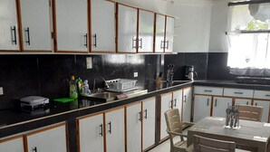 A kitchen with white cabinets, a black countertop, and a dining table with chairs.