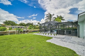 A well-maintained backyard with a lawn, a covered outdoor seating area, and a swimming pool.