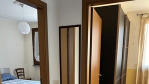 Un dormitorio con una cama, una silla, un espejo y un ventilador de techo.