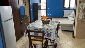 Cocina compacta con comedor, refrigerador y sofá.