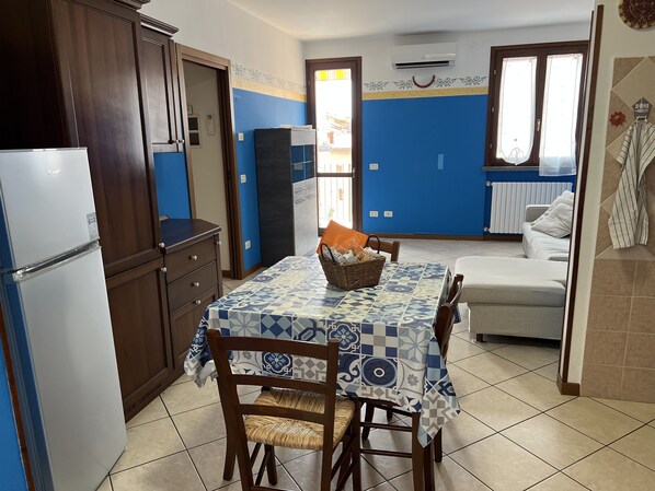 A compact kitchen with a dining area, a refrigerator, and a sofa.