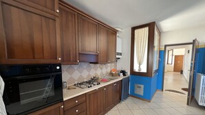 Una cocina con armarios de madera, estufa a gas, horno y piso de baldosas.