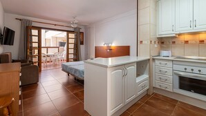 A compact kitchen with white cabinets, a built-in oven, and a small dining area with a table and chairs. - GO2TENERIFE Apart'Elisa Near the beach & Pool view (Arona)