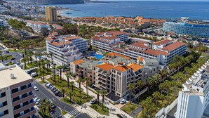 A coastal resort area with multiple hotel buildings, including a prominent hotel with a pool and a view of the sea. - GO2TENERIFE Apart'Elisa Near the beach & Pool view (Arona)
