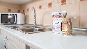 A kitchen with a stainless steel sink, a microwave, and a welcome sign. - GO2TENERIFE Apart'Elisa Near the beach & Pool view (Arona)
