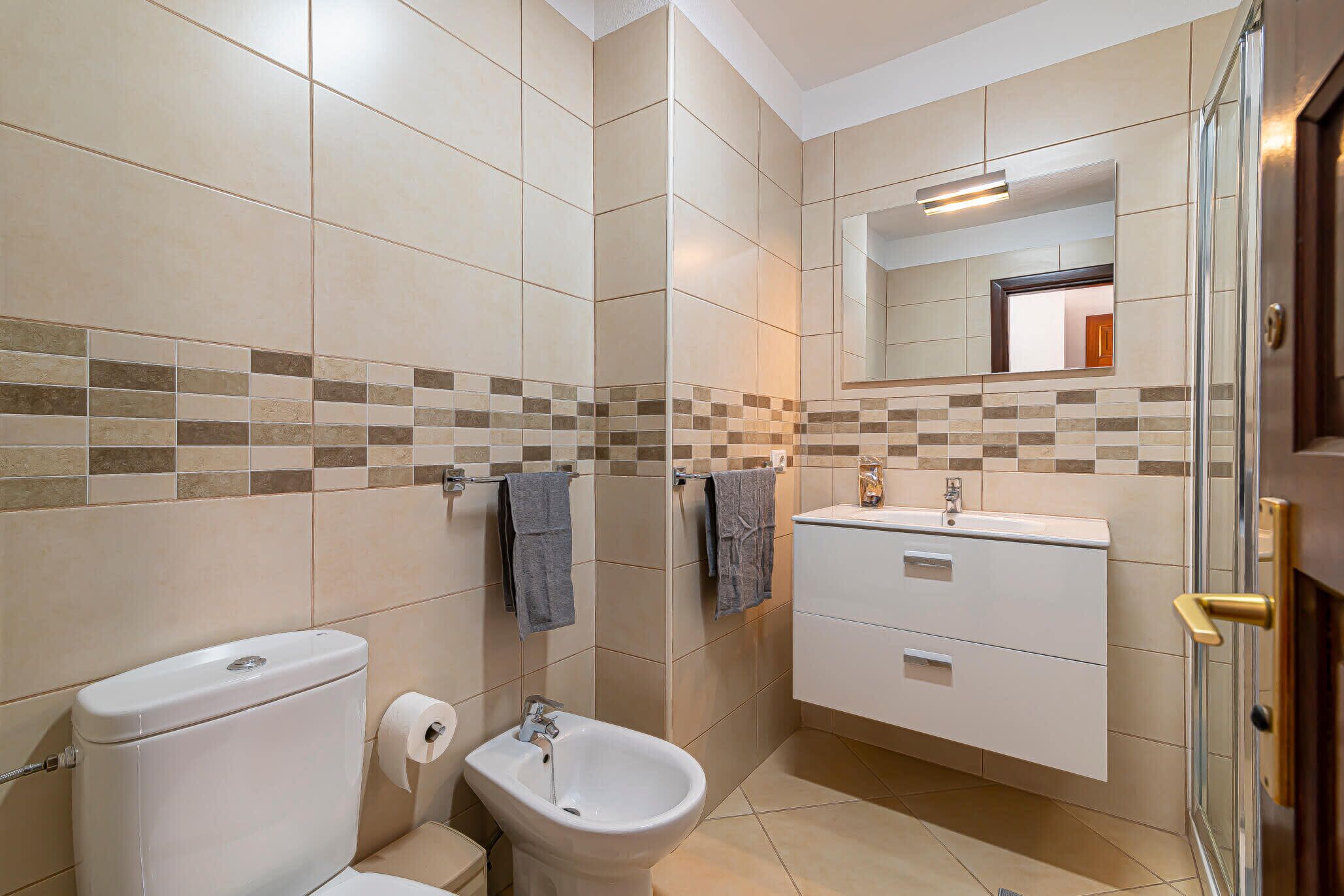 Ein Badezimmer mit Toilette, Bidet, Waschbecken und einem Spiegel darüber.