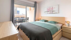 Ett modernt sovrum med en säng, sängbord, ett skrivbord och utsikt från balkongen.