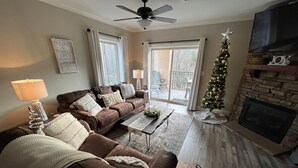 Ein Wohnzimmer mit braunem Ledersofa, einem Couchtisch, einem Kamin und einem Weihnachtsbaum.