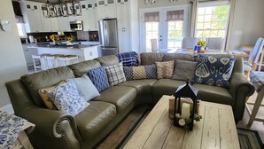 En stue med en vinkelsofa, et sofabord og et spiseområde med et bord og stole.