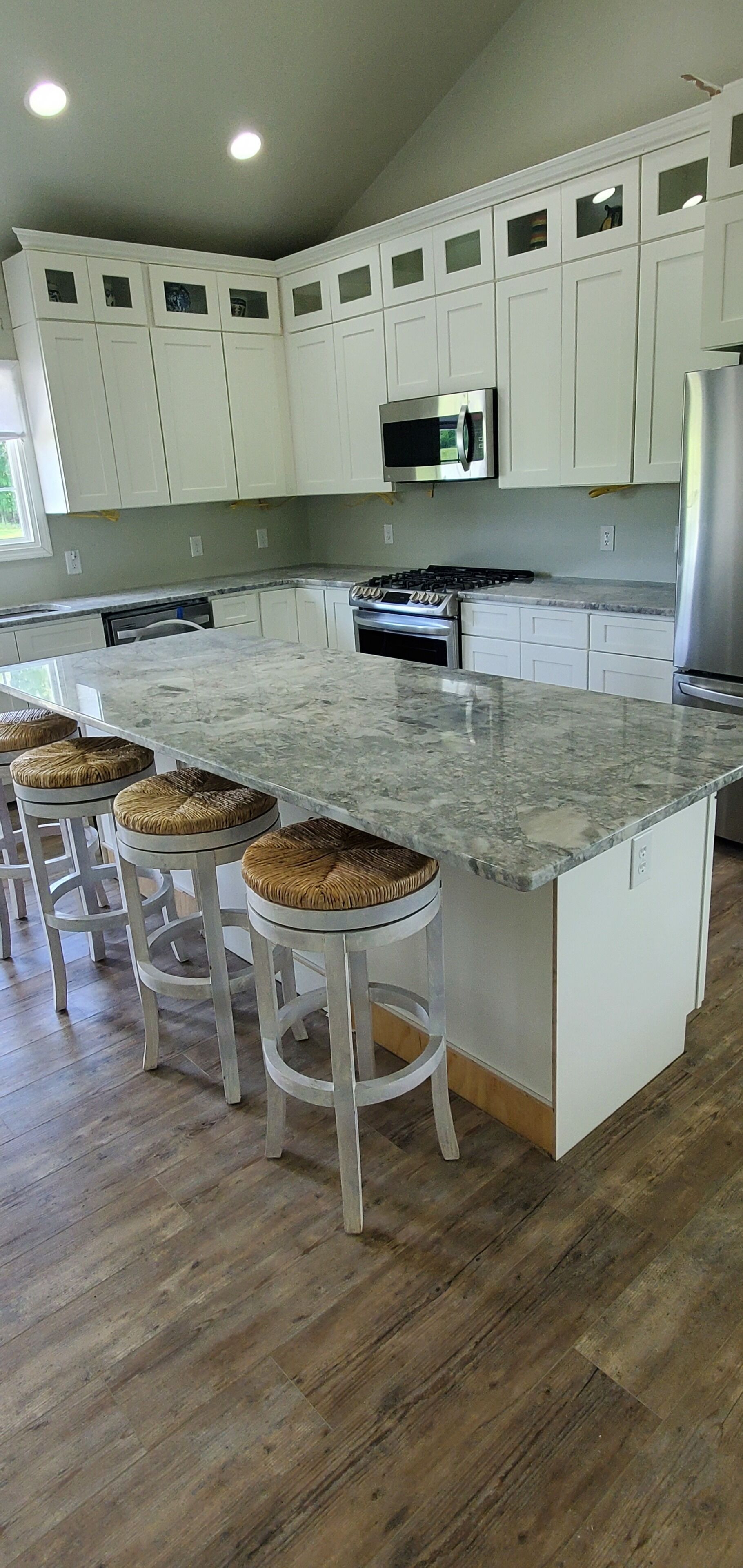 A modern kitchen with white cabinets, a granite countertop, and a central island with stools.