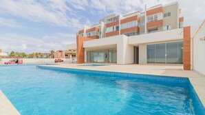 A modern hotel with a swimming pool, a covered patio, and a multi-story building with balconies. - PFL01 - Apartamento 2 Quartos -Vista Mar (Salvador)