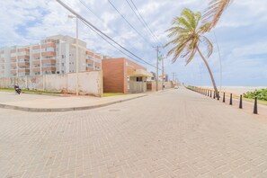 Un vialetto lastricato con una palma, un edificio con balconi e vista sulla spiaggia.