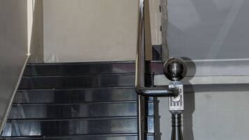 Una escalera con barandilla de metal y una puerta con pomo redondo.