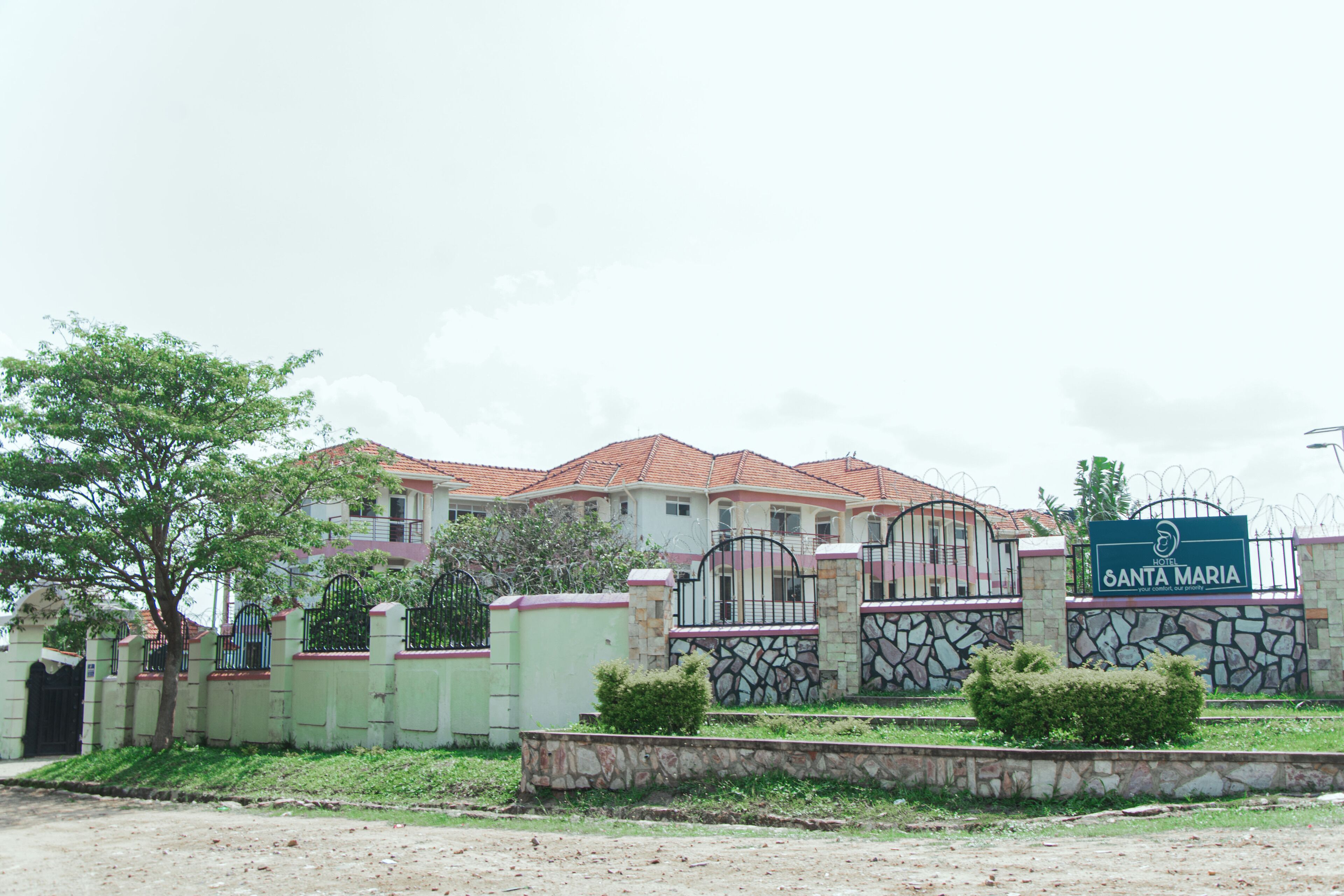 A gated residential area with a house, a sign reading "SANTA MARIA," and a stone wall.