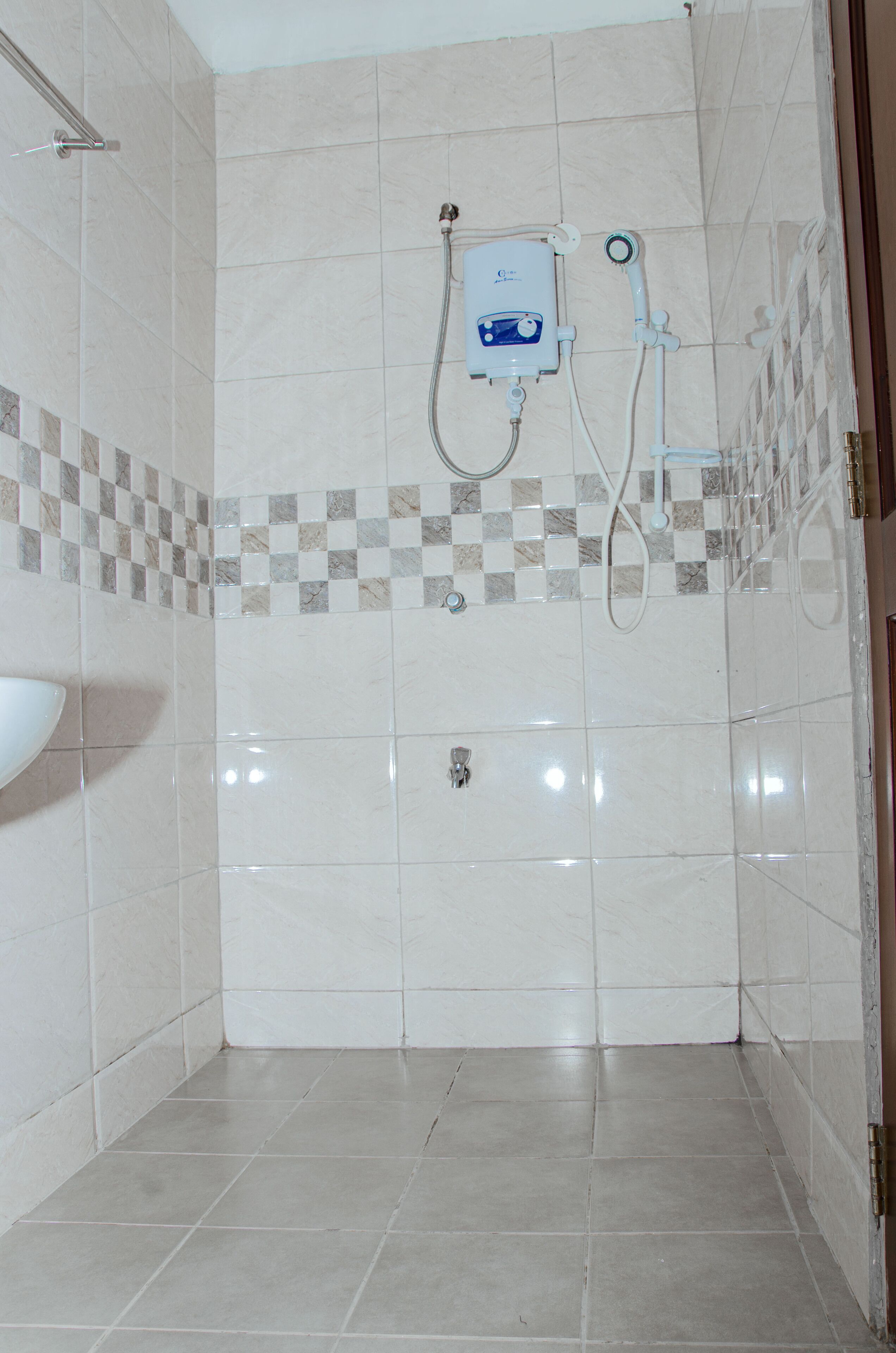 A bathroom with a shower, a sink, and a tiled floor.