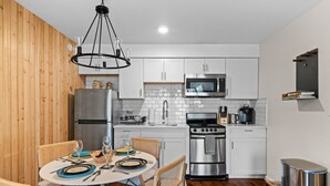 Una cocina moderna con armarios blancos, electrodomésticos de acero inoxidable y una zona de comedor con una mesa redonda y sillas.