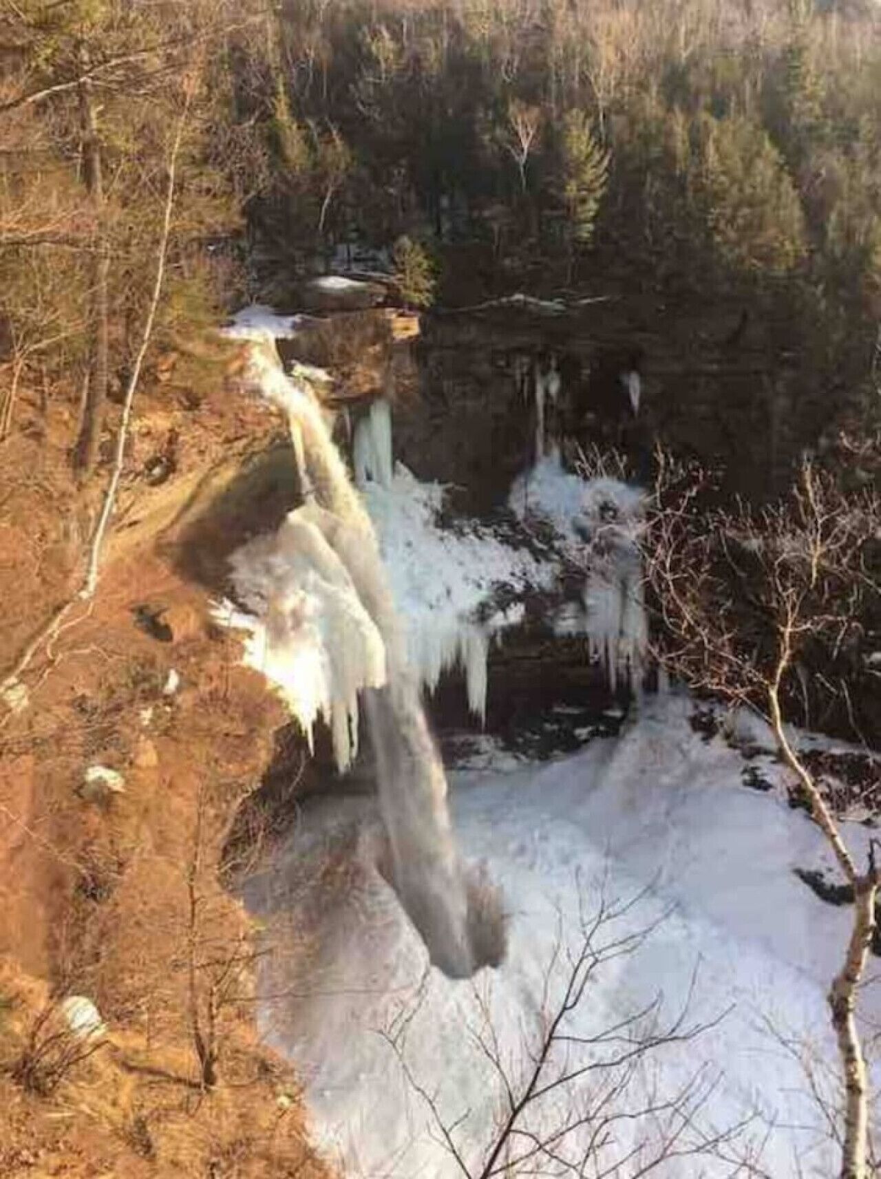 A waterfall cascading over a rocky cliff surrounded by trees.